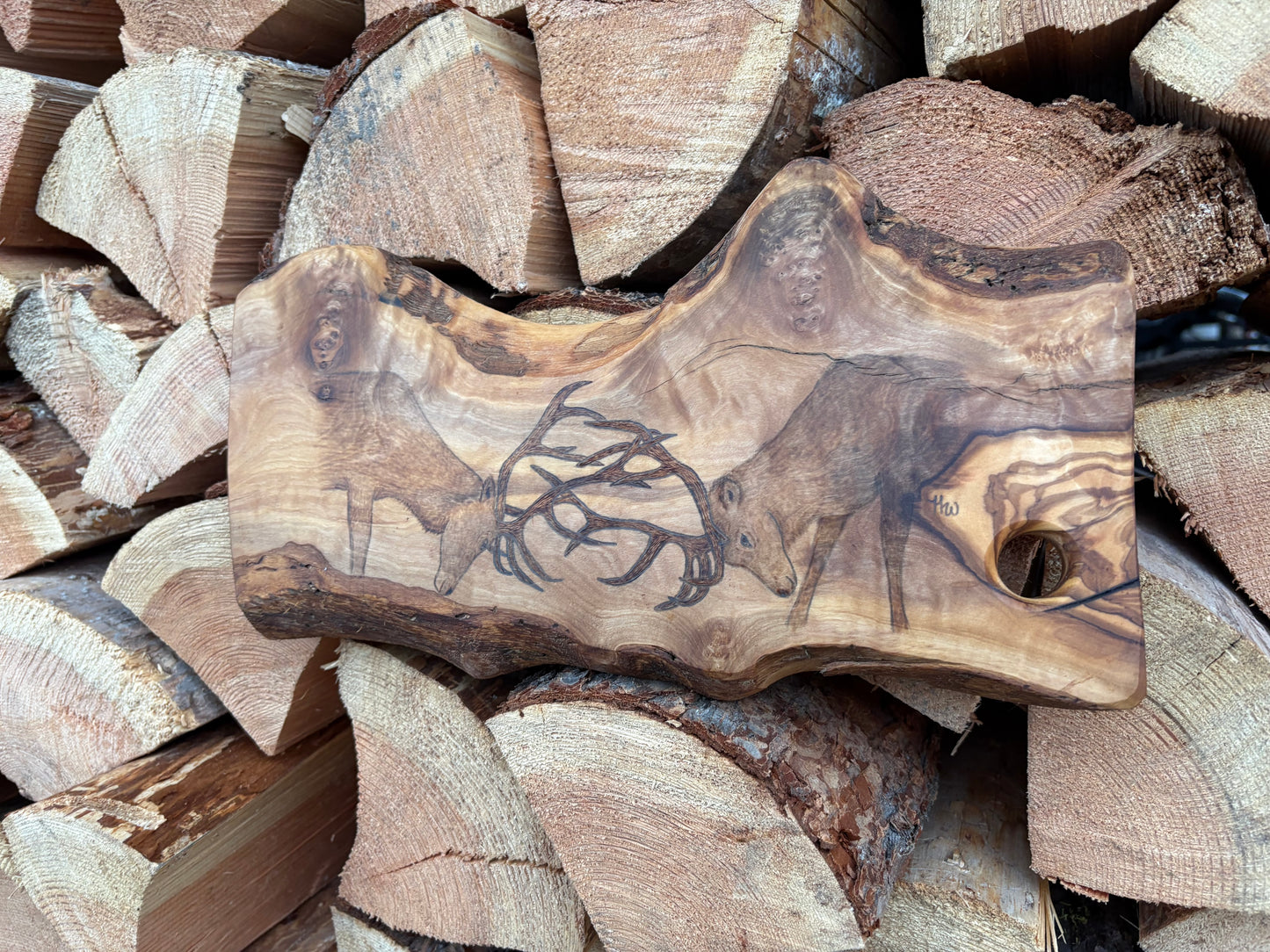 Wooden cutting board with engraved design on a pile of firewood